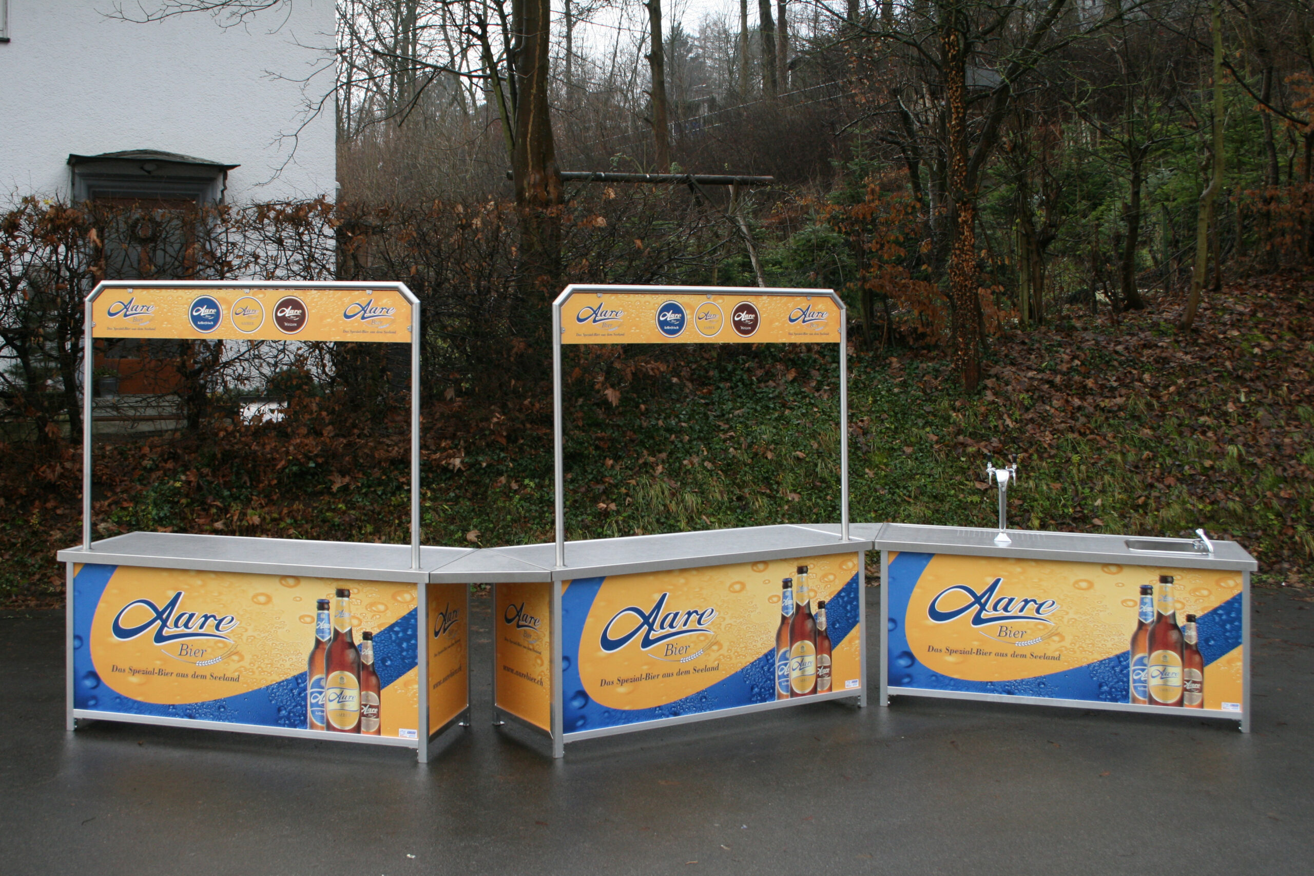 Modulare Ausschanktheke mit EKT-A Eckverbindungsstück und Aare-Bier-Branding, bestehend aus drei Thekenelementen mit Werbeaufsatz und Zapfhahn